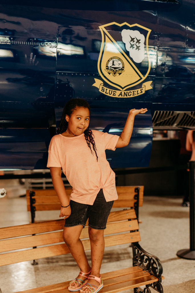 Little girl posing in front of a Blue Angels jet